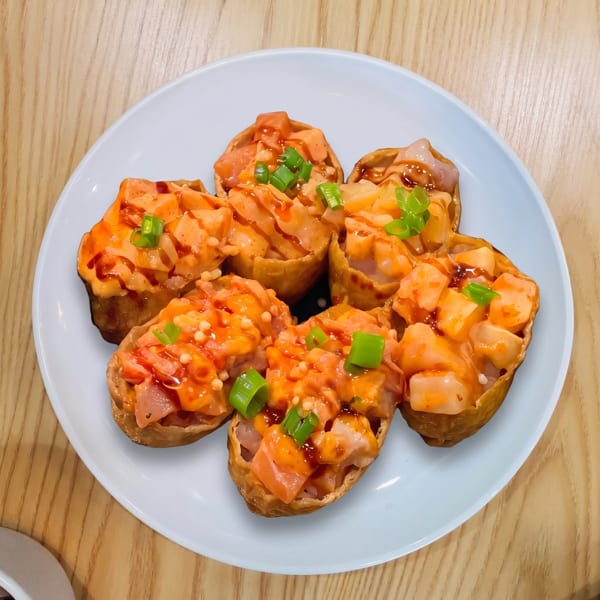 Six pieces of spicy salmon and scallop sushi inari on a light blue plate.
