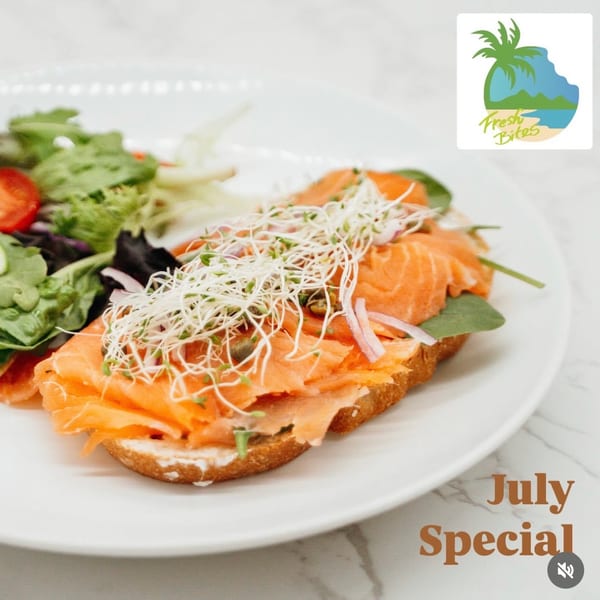Smoked salmon toast with sprouts, red onion, and capers, served with a side salad.